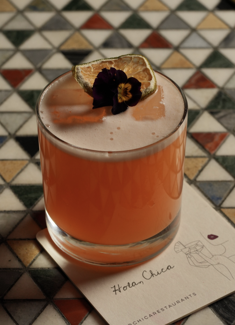 A garnished cocktail on a Hola Chica coaster