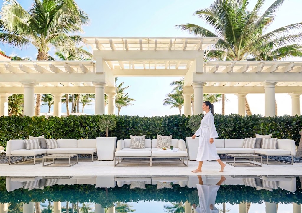 Guest in a robe walking past the spa's oceanfront reflecting pool and colonnade